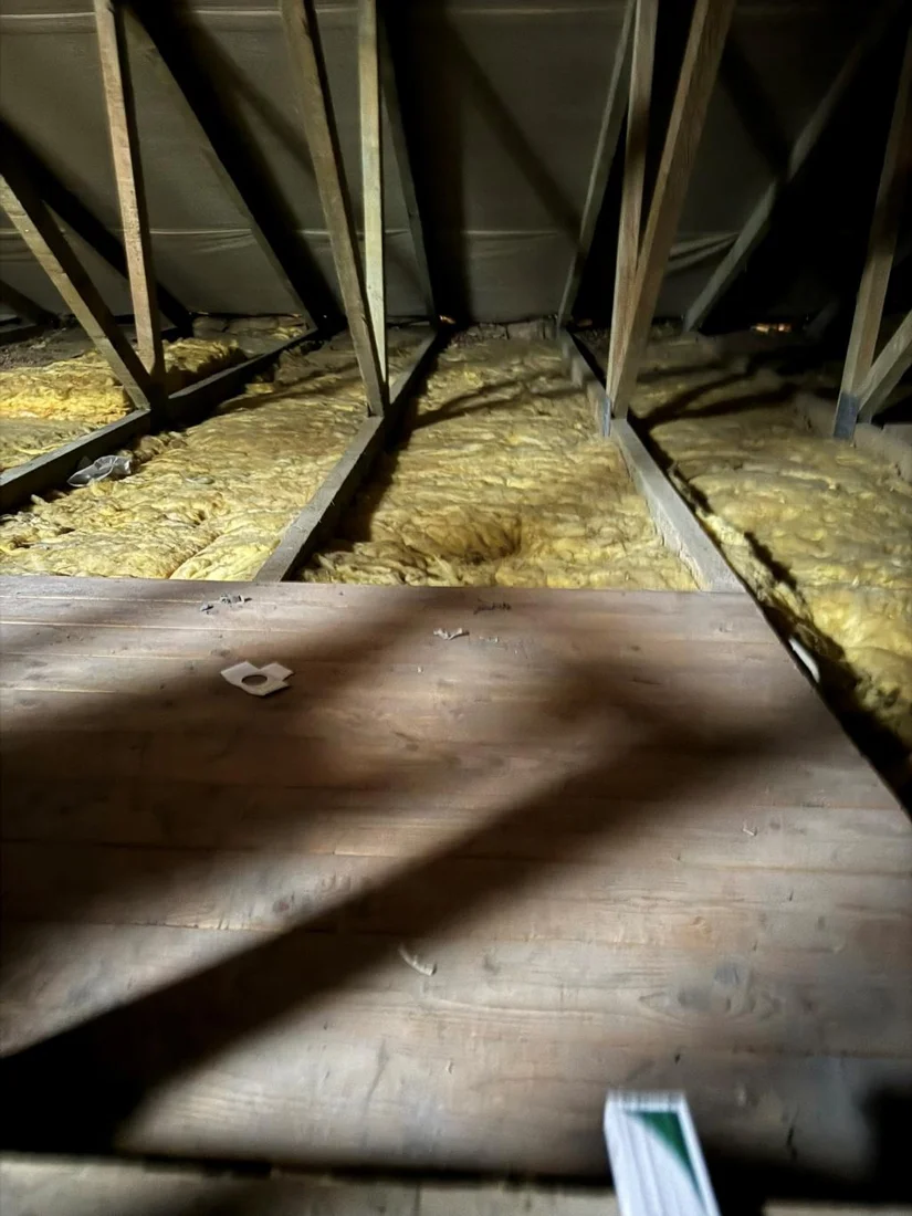 Geöffnete Holzbalkendecke auf einem Dachboden mit sichtbar vorhandener Dämmung