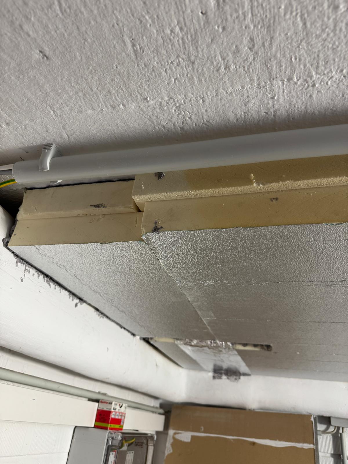 Kellerdecke mit kaschierten Dämmplatten, sichtbaren Plattenkanten und einer Leuchte